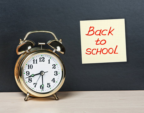 Alarm Clock And Sticker With Text Back To School On The Chalkboa