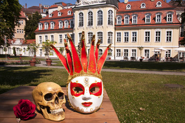Maske und Totenkopf vor historischem Schloss