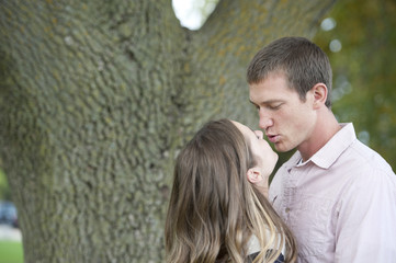 Fototapeta premium Young happy caucasian couple kissing in the park on a sunny day.