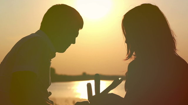 Young couple in love eating ice cream at sunset on the lake
