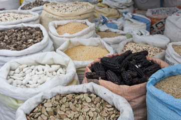 Burlap bags full of a variety of grains on a cloudy day.