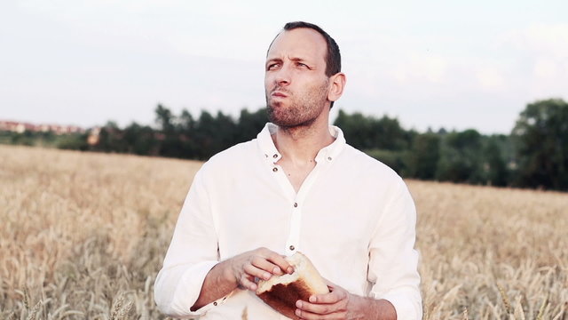 Farmer eating fresh bread in wheat field