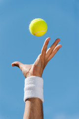 Serving tennis ball.