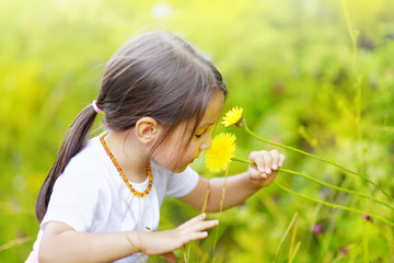 Little girl in the forest smells wonderful flowers and enjoy