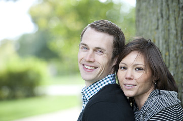 Obraz premium A happy, young and attractive couple looking at the camera on a sunny day at a park
