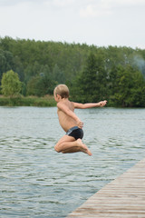Chłopiec skaczący z pomostu do wody 