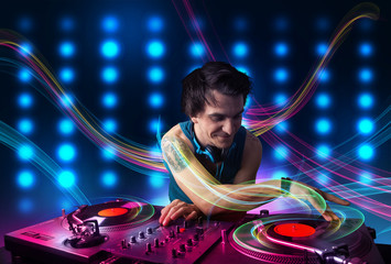 Young Dj mixing records with colorful lights