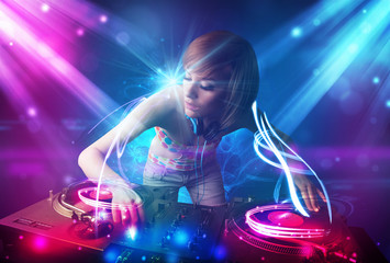 Obraz na płótnie Canvas Energetic Dj girl mixing music with powerful light effects