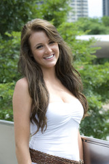 A teen female model outdoors wearing a white dress on a sunny day.