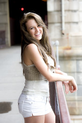 Gorgeous teen model wearing a white top and matching shorts on a sunny day.