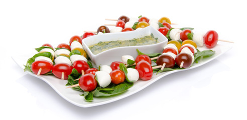 Cherry tomatoes and mozzarella on skewers and a vinaigrette sauc