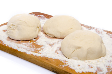 Three balls of pizza dough on a wooden board