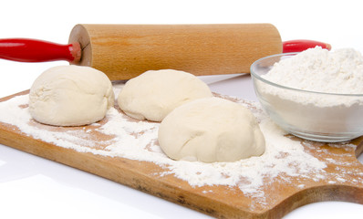 Fototapeta na wymiar Three balls of pizza dough with a cup of flour and a rolling pin