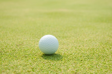Golfball on grass infront of the green