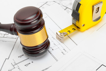 Judge gavel with measure tape above construction blueprint