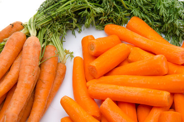 Bunch of fresh carrots and heap of peeled carrots