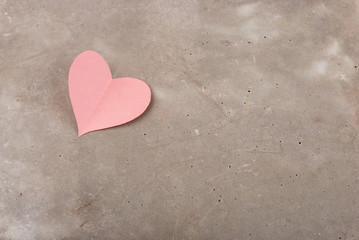 Fototapeta premium Heart of pink paper on the background of gray concrete