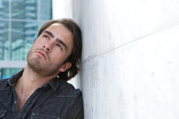 Young man leaning against wall and looking up