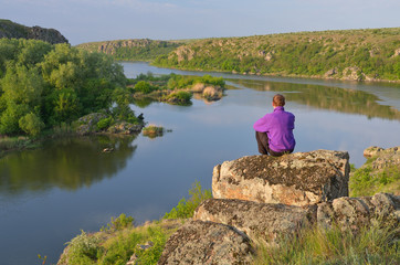 Fototapeta premium Man sits on a rock above the river