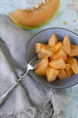 pieces of melon on bowl and slices on vintage scraped background