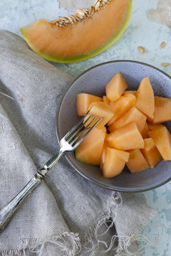 pieces of melon on bowl and slices on vintage scraped background