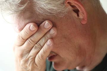 Man covers face with hand