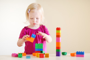 Cute toddler girl playing with colorful blocks