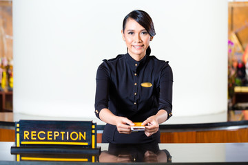 Asian woman in uniform at hotel reception desk