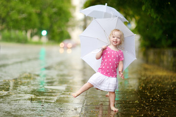 Cute little toddler girl having fun under a rain © MNStudio