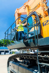 Asian worker on shovel excavator construction site