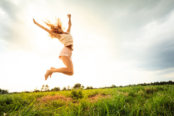 Jumping girl at field in summer