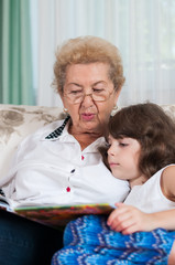 Nice elderly woman grandmother reading story to sweet young gran