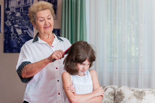 Nice grandmother combing upset granddaughter's hair