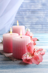 Beautiful candles with flowers on wooden background