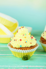 Tasty cup cake with cream on blue wooden table