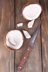 Broken coconut with knife on wooden background