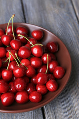 Sweet cherries  on plate on wooden background