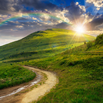 mountain path uphill to the sky at sunset with rainbow