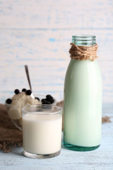 Glass bottle of milk and cottage cheese on wooden background