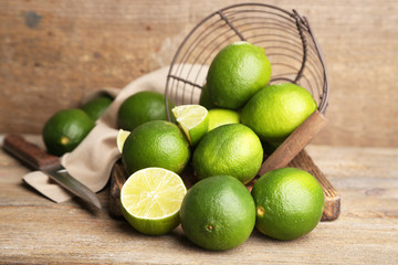 Fresh juicy limes in basket on old wooden background