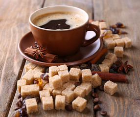 Brown sugar, spices and cup of coffee on wooden background