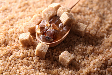 Reed sugar in wooden spoon on brown crystal sugar background