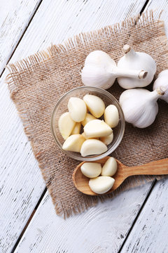 Fresh sliced garlic in glass bowl on wooden background