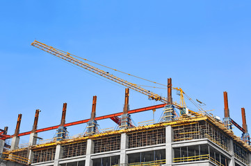 Crane and building construction site against blue sky