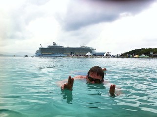 men swimming in the sea with the big ship in the vackground