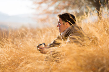 man sitting in tall grass in autumn