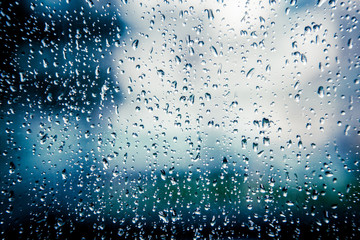 Fototapeta na wymiar Many raindrops on blue light window glass