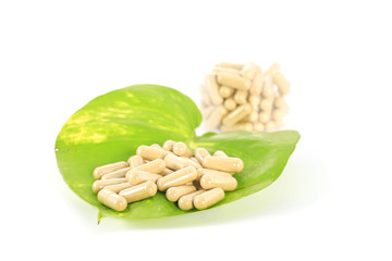 herb capsule on green leaf isolated ,white background
