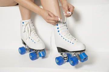 Roller skater tying laces on her quad wheel boots