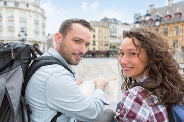 Couple of young attractive tourists watching map